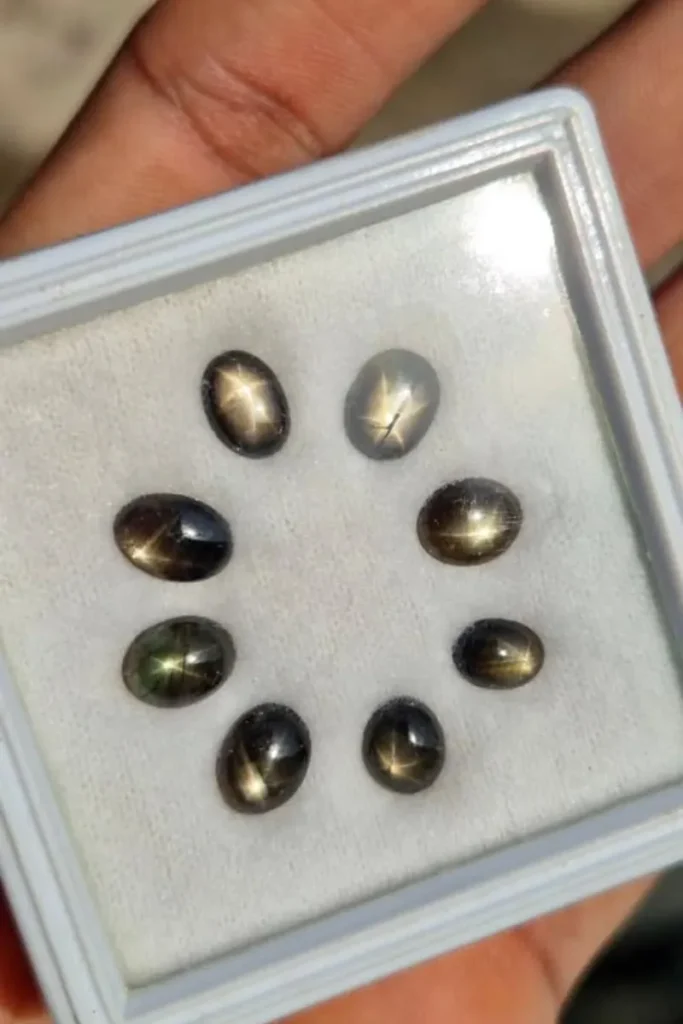 A collage of hands holding various natural star sapphire cabochons showing distinct six-ray asterism stars, overlaid with title text reading "What Does a Star Sapphire Symbolize? A Complete Guide".