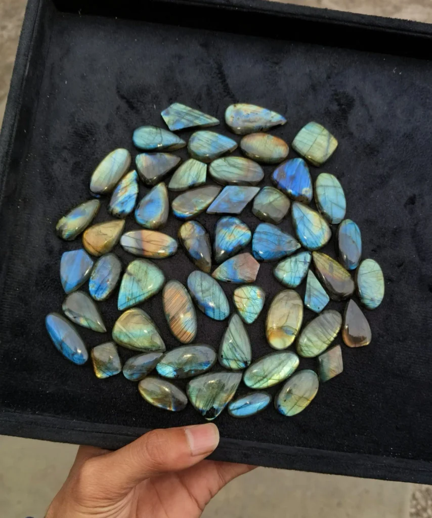 Wholesale parcel of polished natural labradorite cabochons in mixed geometric and teardrop shapes with blue-gold flash.
