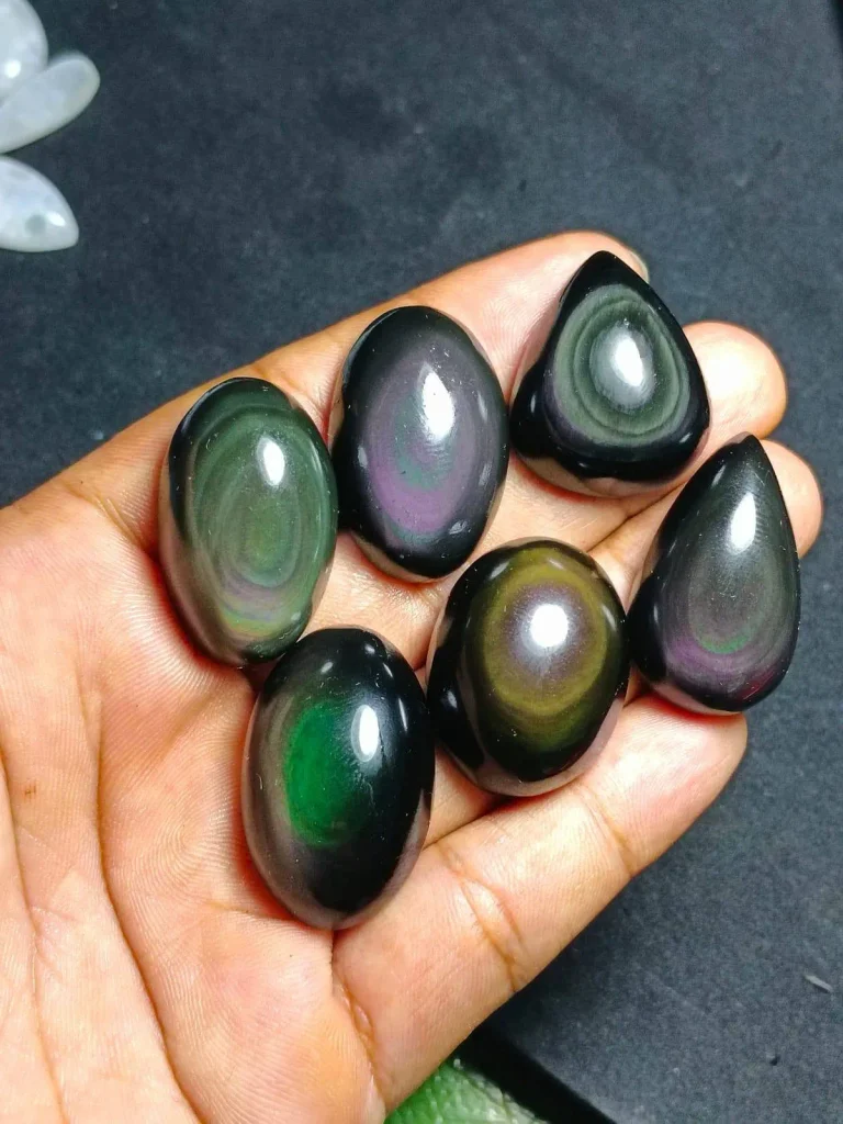 Wholesale parcel of natural polished rainbow obsidian flat-back cabochons with green and magenta iridescent sheen for jewelry making.
