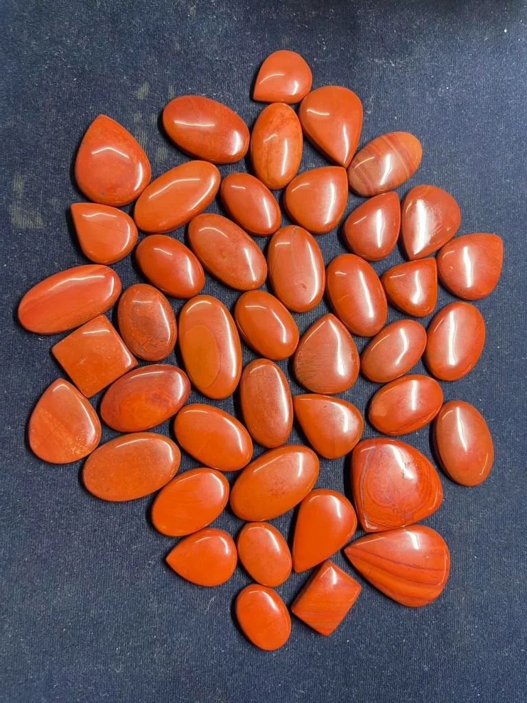 Wholesale parcel of polished natural red jasper flat-back cabochons with high-shine luster for jewelry making.
