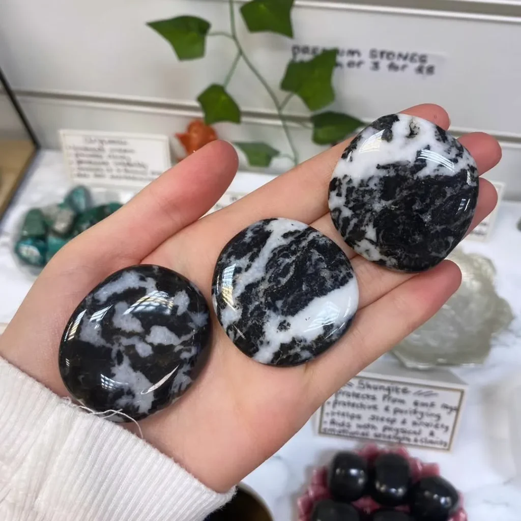 Natural polished zebra jasper palm stones and worry stones displaying bold monochrome black and white patterns for grounding and meditation.